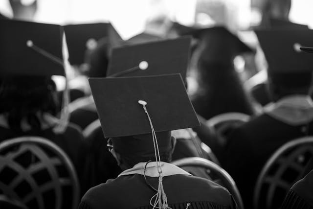 Studenten in Talaren und Mortarboards sitzen bei der Abschlussfeier