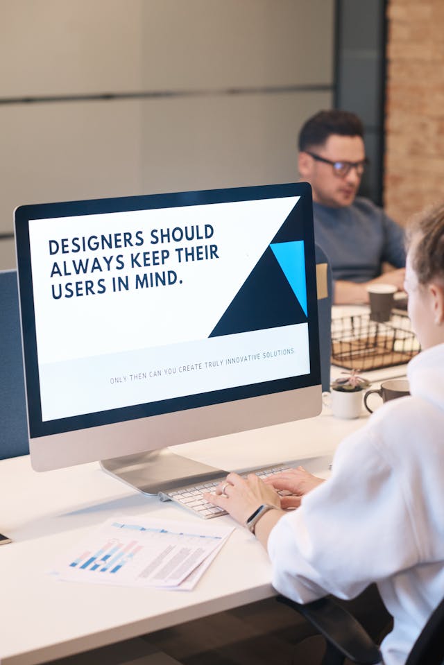 a ux designer working on computer with monitor showing message