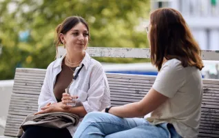 Studentinnen unterhalten sich auf einer Bank über ihre Soziale-Arbeit-Studium-Erfahrungen