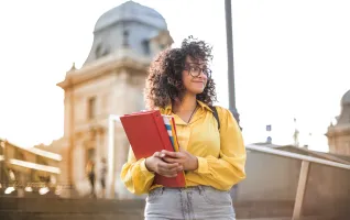 Universitätsstudent in gelber Jacke, der Bücher hält