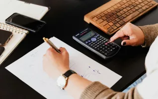 Accountant using calculator and writing numbers down on paper