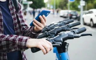Close-up of a man using mobile app to rent electric scooter sustainable mobility