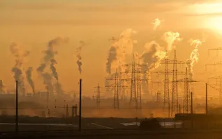 Electric towers during golden hour with carbon emission pollution in background