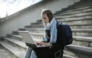Woman sitting on concrete stairs using her laptop for distance learning studies