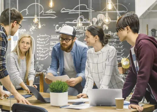 Eine Gruppe junger Menschen diskutiert in einem modernen Büroraum