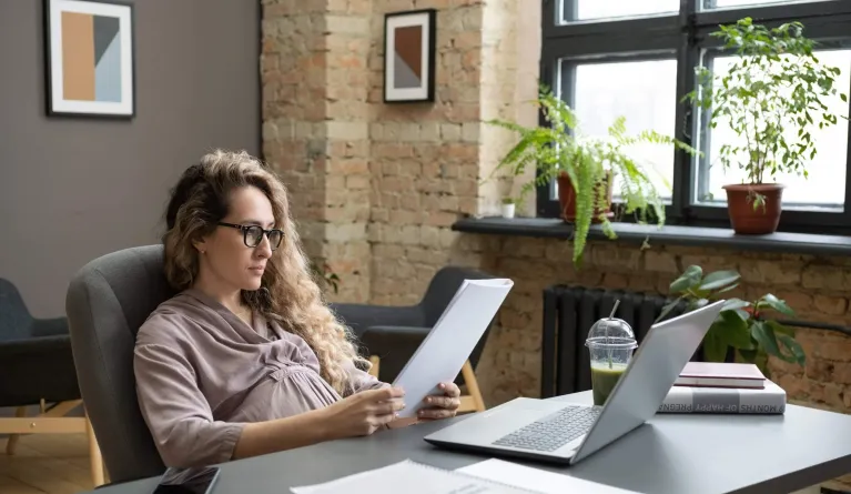 Junge Frau lernt schwanger im Studium vor Laptop