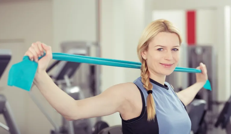 Frau macht Sportpsychologie-Übung mit Theraband als Teil psychologischer Gesundheitsförderung