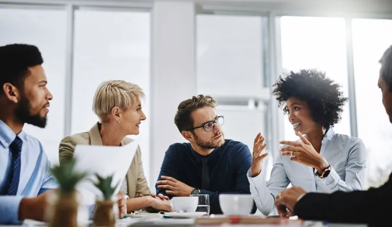 Studierende im Master MBA sitzen an einem Konferenztisch in einem hellen Büro und diskutieren in der Praxis über die Inhalte aus dem Studium an der PFH Göttingen.