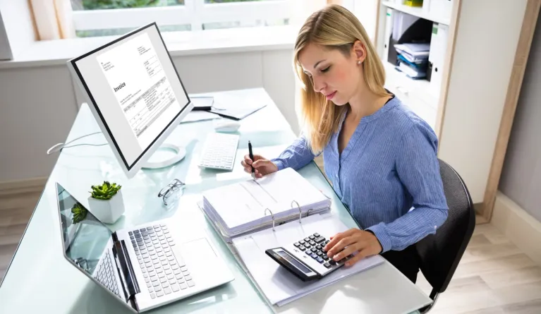 Mitarbeiterin arbeitet am Schreibtisch im Rechnungswesen nach ihrem Fernstudium-Abschluss