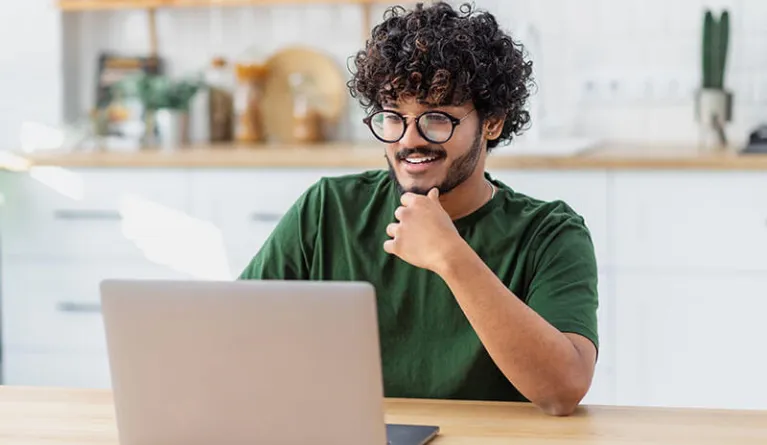 Student sieht sich am Laptop Inhalte des Fernstudienganges Wirtschaftsinformatik im Bachelor Fernstudium an 