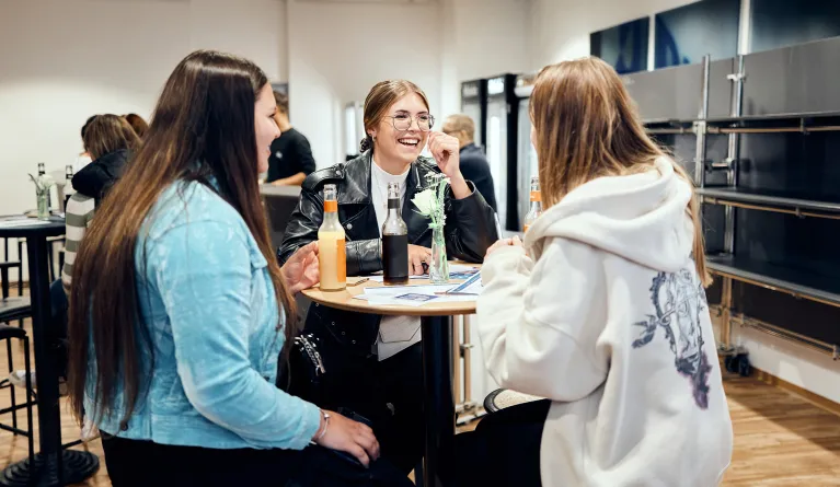 Studieninteressierte unterhalten sich an einem Tisch.