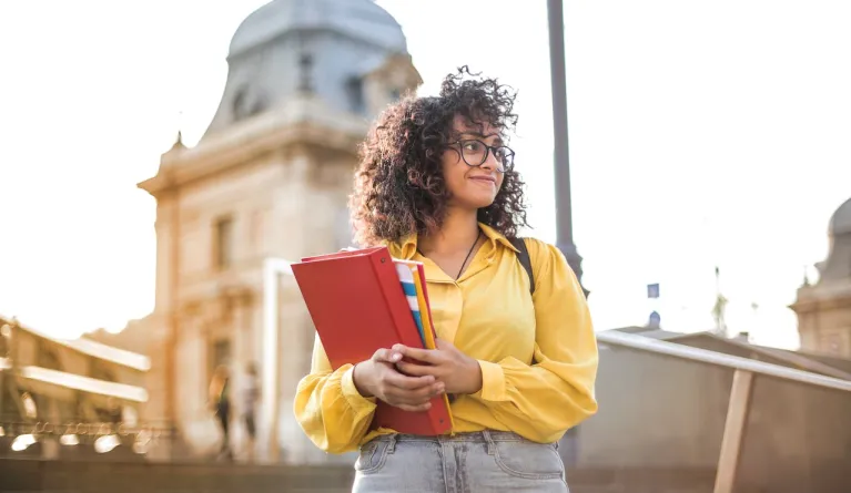 Universitätsstudent in gelber Jacke, der Bücher hält