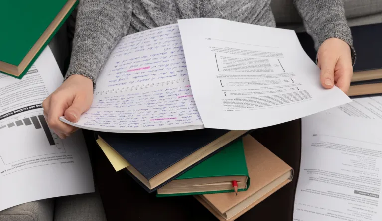 Close-up of a person holding university thesis research papers