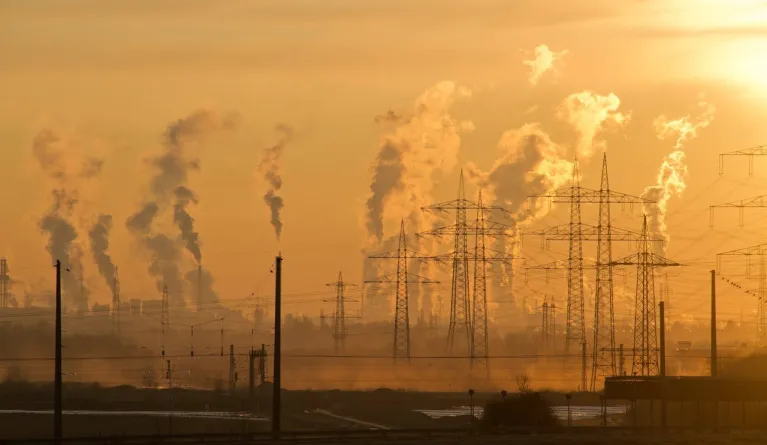 Electric towers during golden hour with carbon emission pollution in background