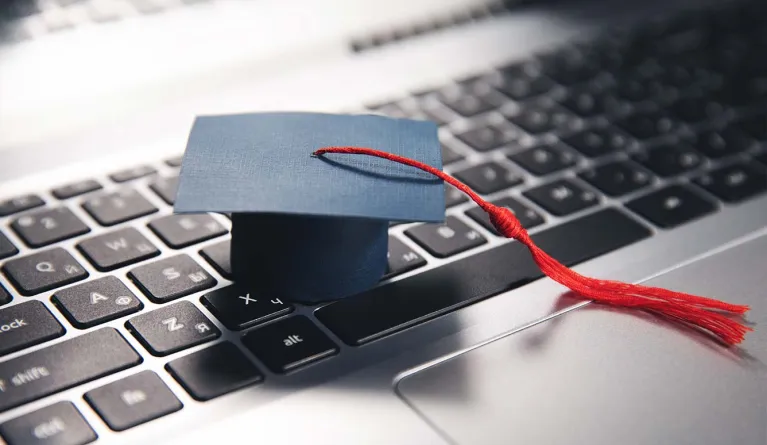 Abschluss-Hut auf einer Laptop-Tastatur symbolisiert die Fernstudium-Anerkennung