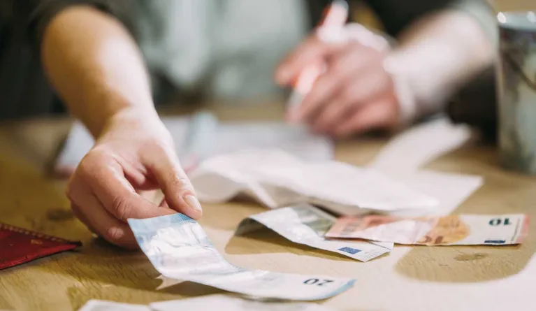Studieninteressent legt vor sich Bargeld als Teil der Studienkosten auf den Tisch