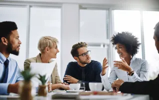 Studierende im Master MBA sitzen an einem Konferenztisch in einem hellen Büro und diskutieren in der Praxis über die Inhalte aus dem Studium an der PFH Göttingen.