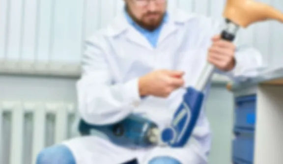 Ein Student im weißen Kittel schraubt an einer Prothese im Masterstudium Medizinische Orthobionik an der PFH Göttingen.