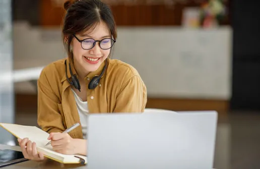 Studentin sieht Fernstudium Inhalte aus dem Unternehmensrecht Master am Laptop