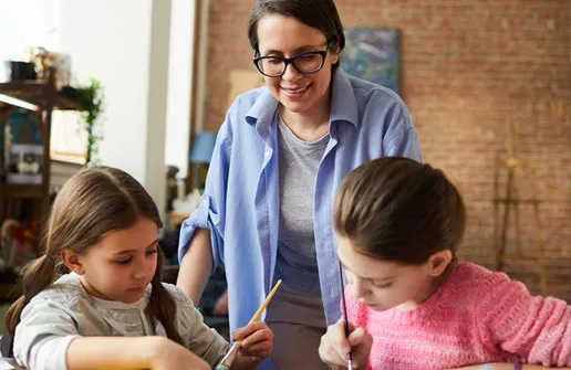 Kinderpädagoge mit abgeschlossenem Kindheitspädagogik Fernstudium arbeitet mit zwei Schülerinnen