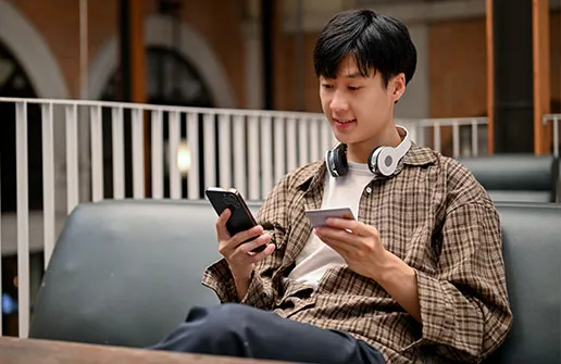 Heilpädagogik-Student mit Kreditkarte in der Hand freut sich über erfolgreiche Fernstudium-Finanzierung