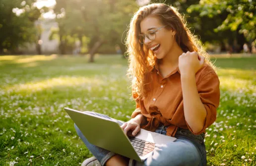 Eine Studierende im Fernstudium am Laptop draußen.